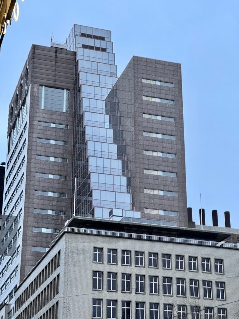 a clock on a pole in front of a tall building